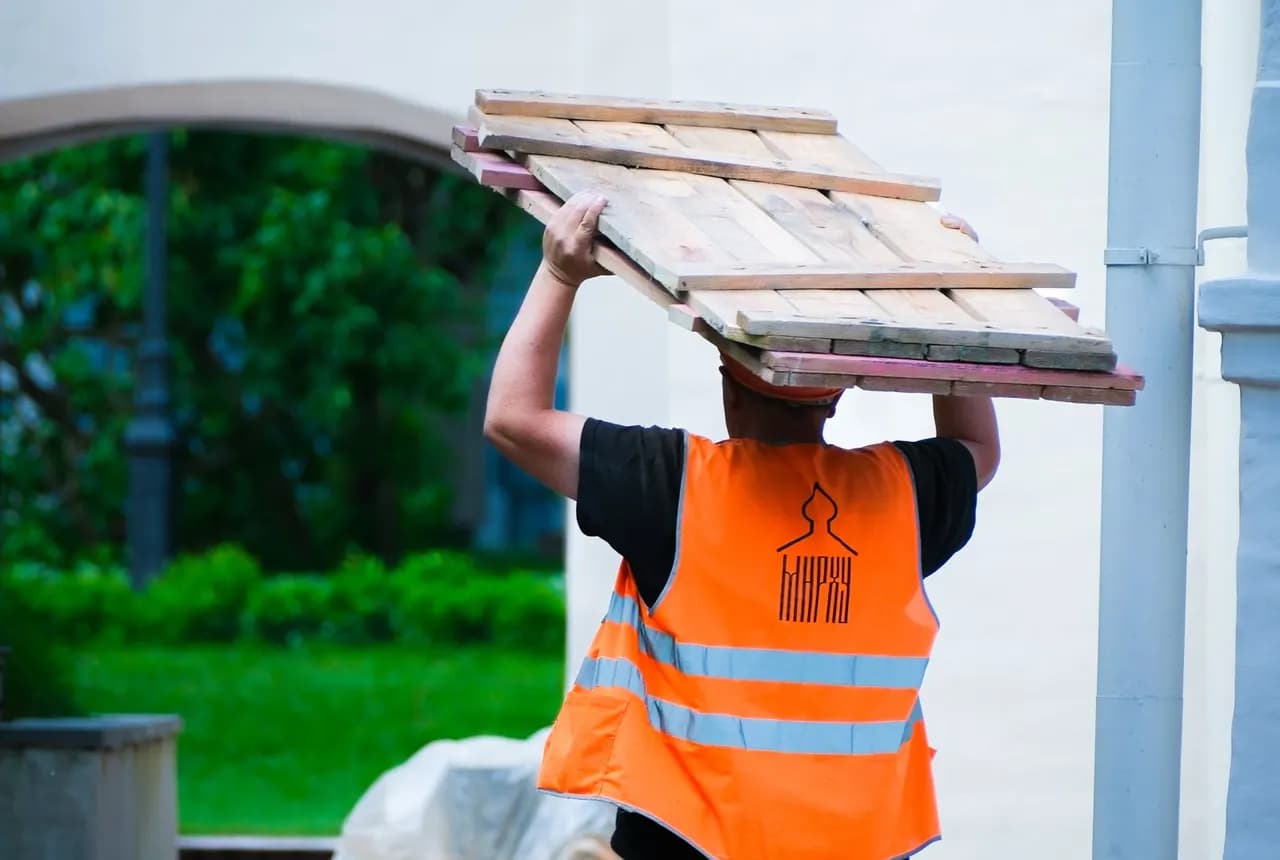 Construction worker carrying timber material outdoors